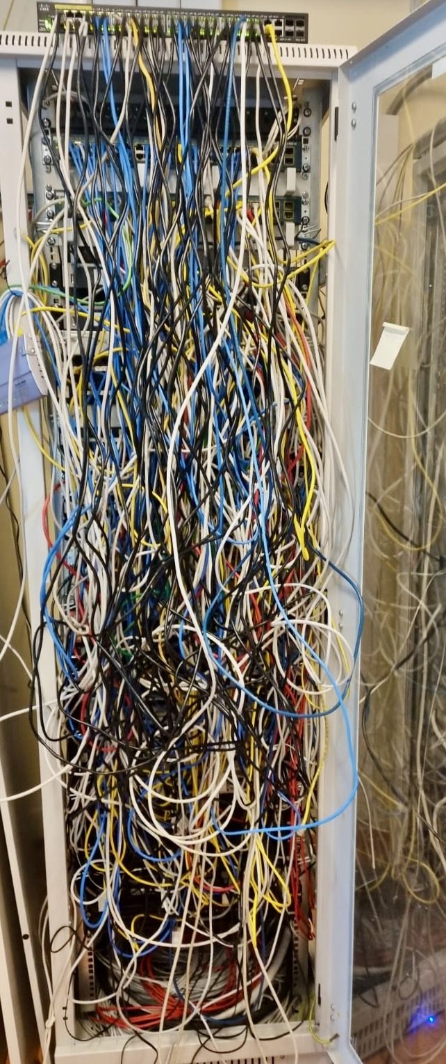 Zaniedbana szafa serwerowa klienta — splątane kable, brak etykiet, nieczytelna instalacja